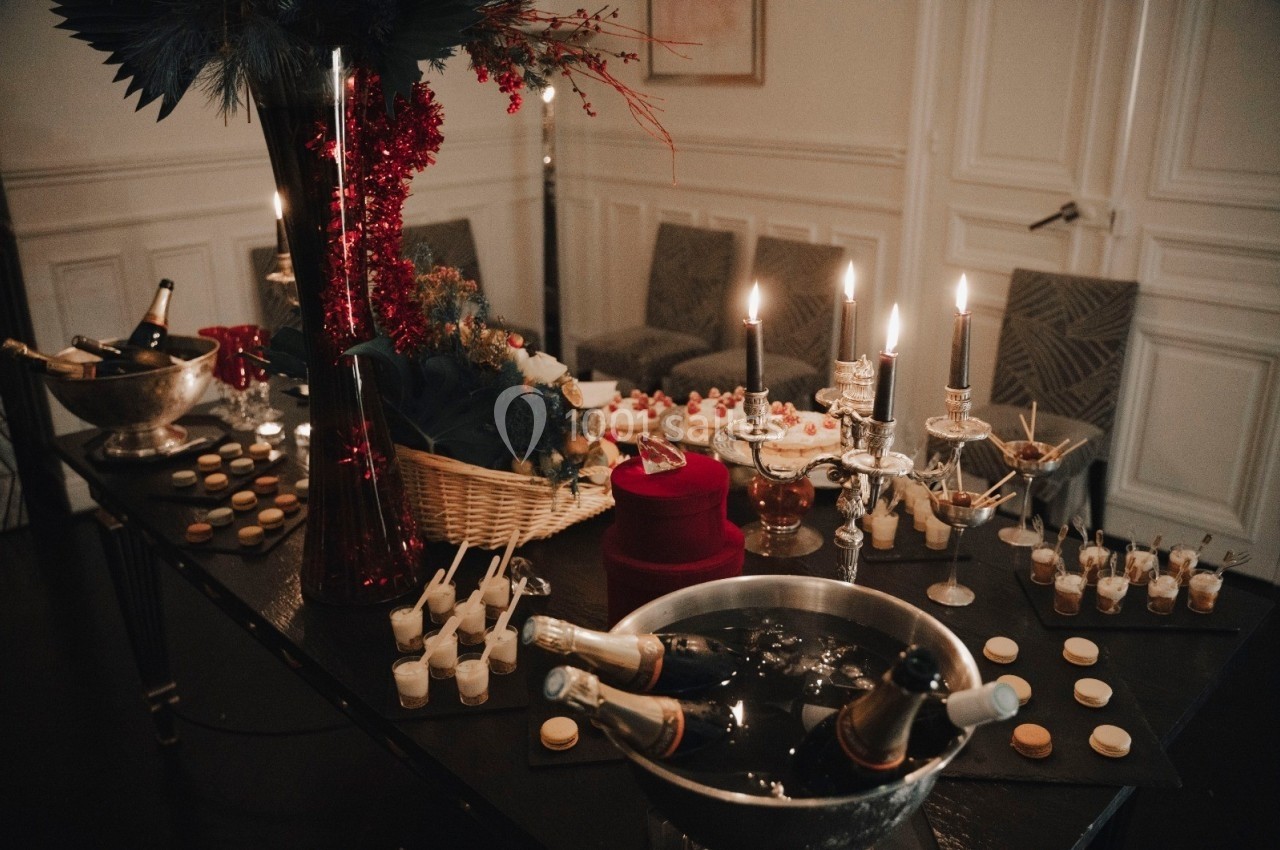 Table festive décorée avec des bougies, des desserts, des macarons et des bouteilles de champagne dans des seaux à glace.