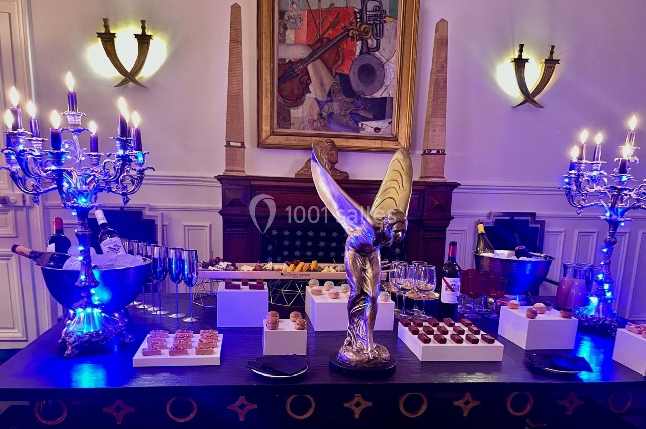 Table décorée avec chandeliers, sculpture et assortiment de desserts et boissons dans un cadre élégant.