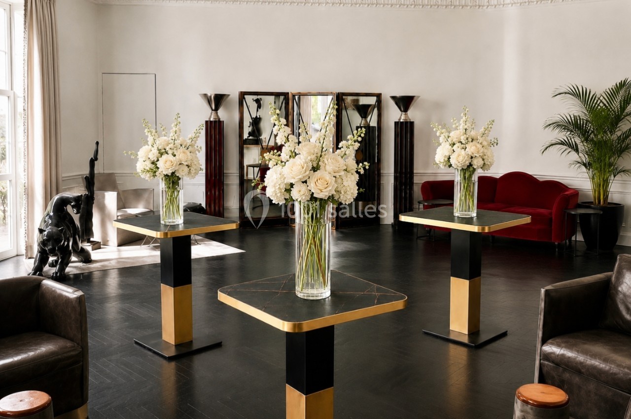 Location salle Paris 8 (Paris) - Le Loft Triangle d'Or Champs-Élysées #49 Salle élégante avec tables modernes ornées de bouquets blancs, canapé rouge, statue et plantes en arrière-plan.