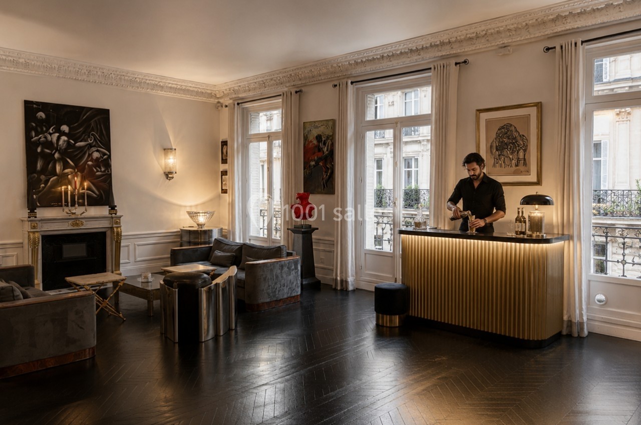 Location salle Paris 8 (Paris) - Le Loft Triangle d'Or Champs-Élysées #50 Un homme prépare une boisson derrière un comptoir doré dans un salon élégant avec parquet sombre et œuvres d'art.