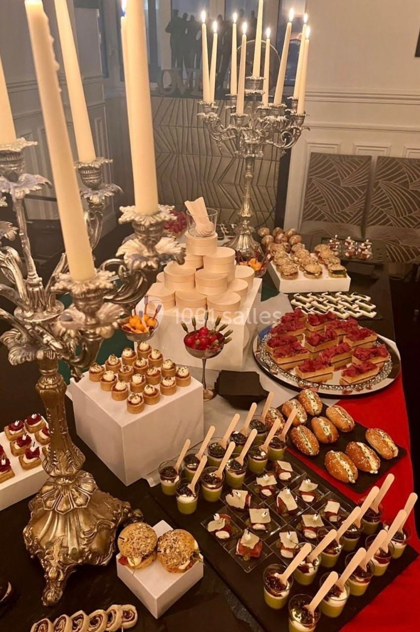Location salle Paris 8 (Paris) - Le Loft Triangle d'Or Champs-Élysées #56 Table garnie de desserts variés, bougies sur chandeliers en argent, ambiance élégante et festive.