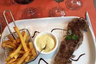 Salle de restaurant lumineuse avec table dressée, grandes fenêtres donnant sur un jardin et murs en briques.