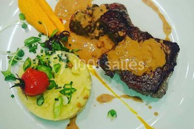 Salle de restaurant lumineuse avec table dressée, grandes fenêtres donnant sur un jardin et murs en briques.