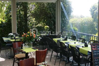 Salle de restaurant lumineuse avec table dressée, grandes fenêtres donnant sur un jardin et murs en briques.