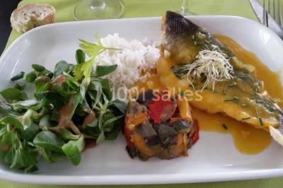 Salle de restaurant lumineuse avec table dressée, grandes fenêtres donnant sur un jardin et murs en briques.
