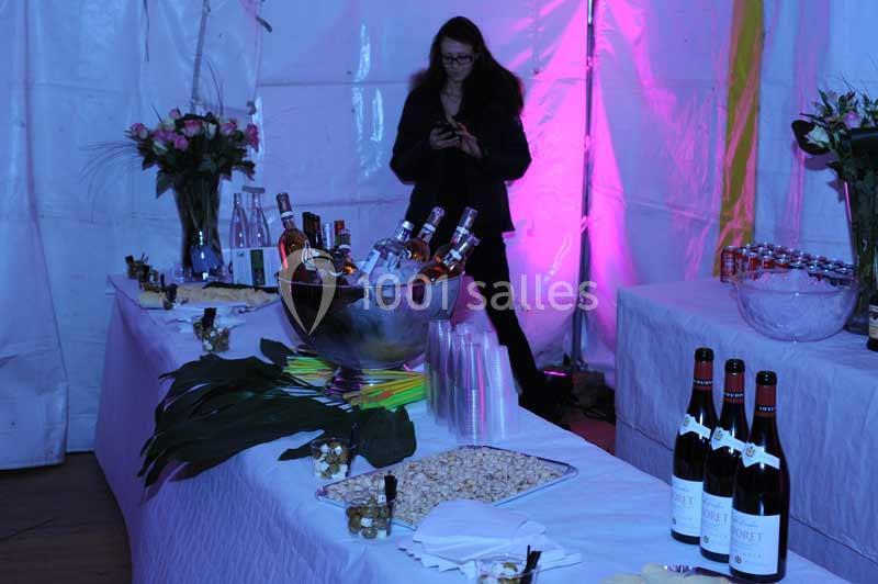 Table dressée avec des bouteilles de vin, un seau à glace rempli de boissons et des décorations florales dans une ambiance…
