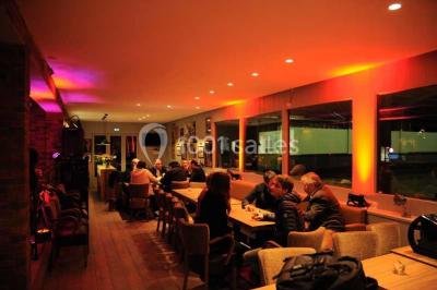 Salle de restaurant lumineuse avec table dressée, grandes fenêtres donnant sur un jardin et murs en briques.