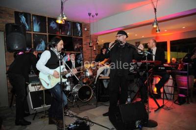 Salle de restaurant lumineuse avec table dressée, grandes fenêtres donnant sur un jardin et murs en briques.