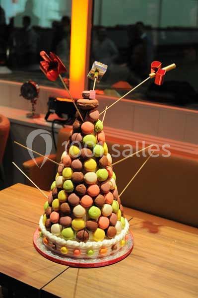 Pyramide de macarons colorés montée sur une base conique, décorée de petits moulins à vent et présentée sur une table.