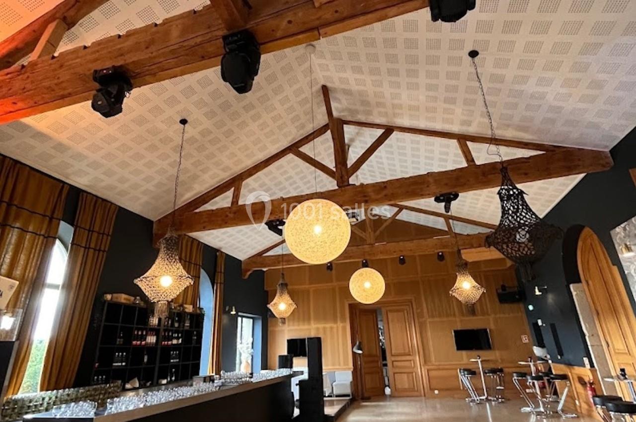 Plafond avec poutres en bois apparentes dans une salle moderne, équipée d'un bar et de luminaires suspendus.