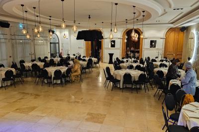 Vue nocturne d'une fête en plein air avec des lumières colorées, une piste de danse et des participants rassemblés.