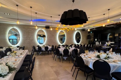 Vue nocturne d'une fête en plein air avec des lumières colorées, une piste de danse et des participants rassemblés.