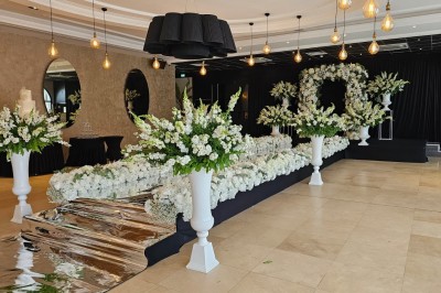 Salle de réception élégante avec tables dressées, décor floral et éclairage suspendu dans une ambiance lumineuse.