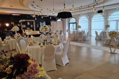 Salle de réception élégante avec tables dressées, décor floral et éclairage suspendu dans une ambiance lumineuse.