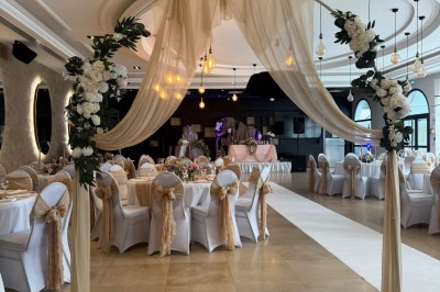 Salle de réception élégante avec tables dressées, décor floral et éclairage suspendu dans une ambiance lumineuse.
