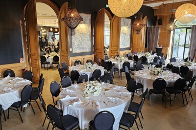 Salle de réception élégante avec tables dressées, décor floral et éclairage suspendu dans une ambiance lumineuse.