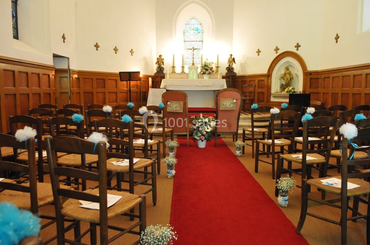 Salle de cérémonie décorée pour un mariage, avec des chaises alignées, une allée rouge et un autel en arrière-plan.