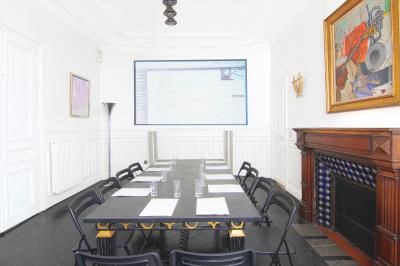 Salle à manger élégante avec table noire ornée, chandeliers, sculpture de panthère et tableau coloré au mur.