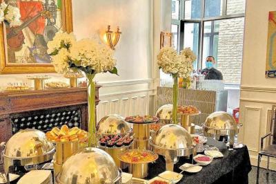 Salle à manger élégante avec table noire ornée, chandeliers, sculpture de panthère et tableau coloré au mur.