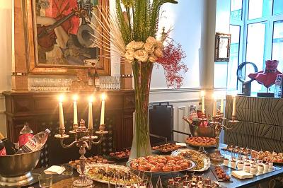 Salle à manger élégante avec table noire ornée, chandeliers, sculpture de panthère et tableau coloré au mur.