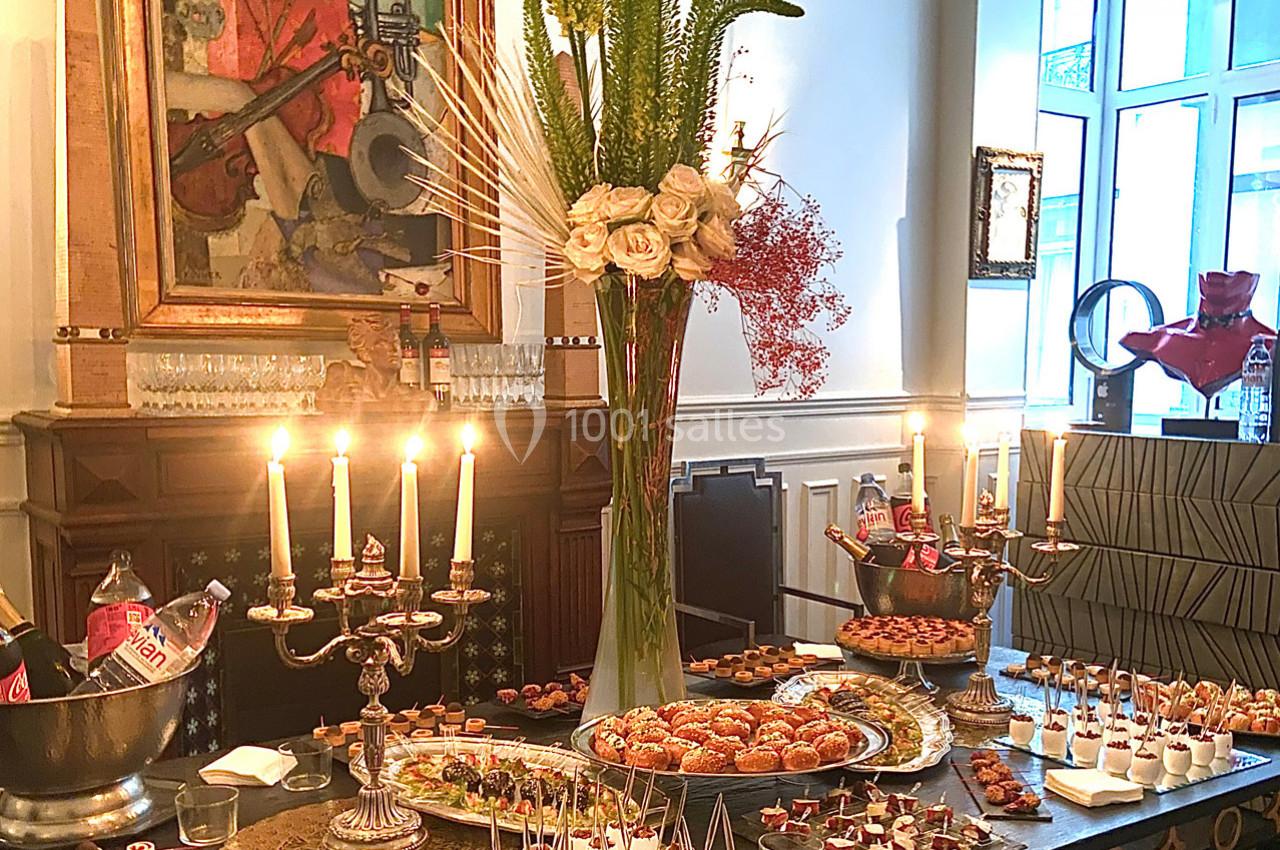 Table garnie de mets variés, bougies allumées et décoration florale dans un intérieur élégant.