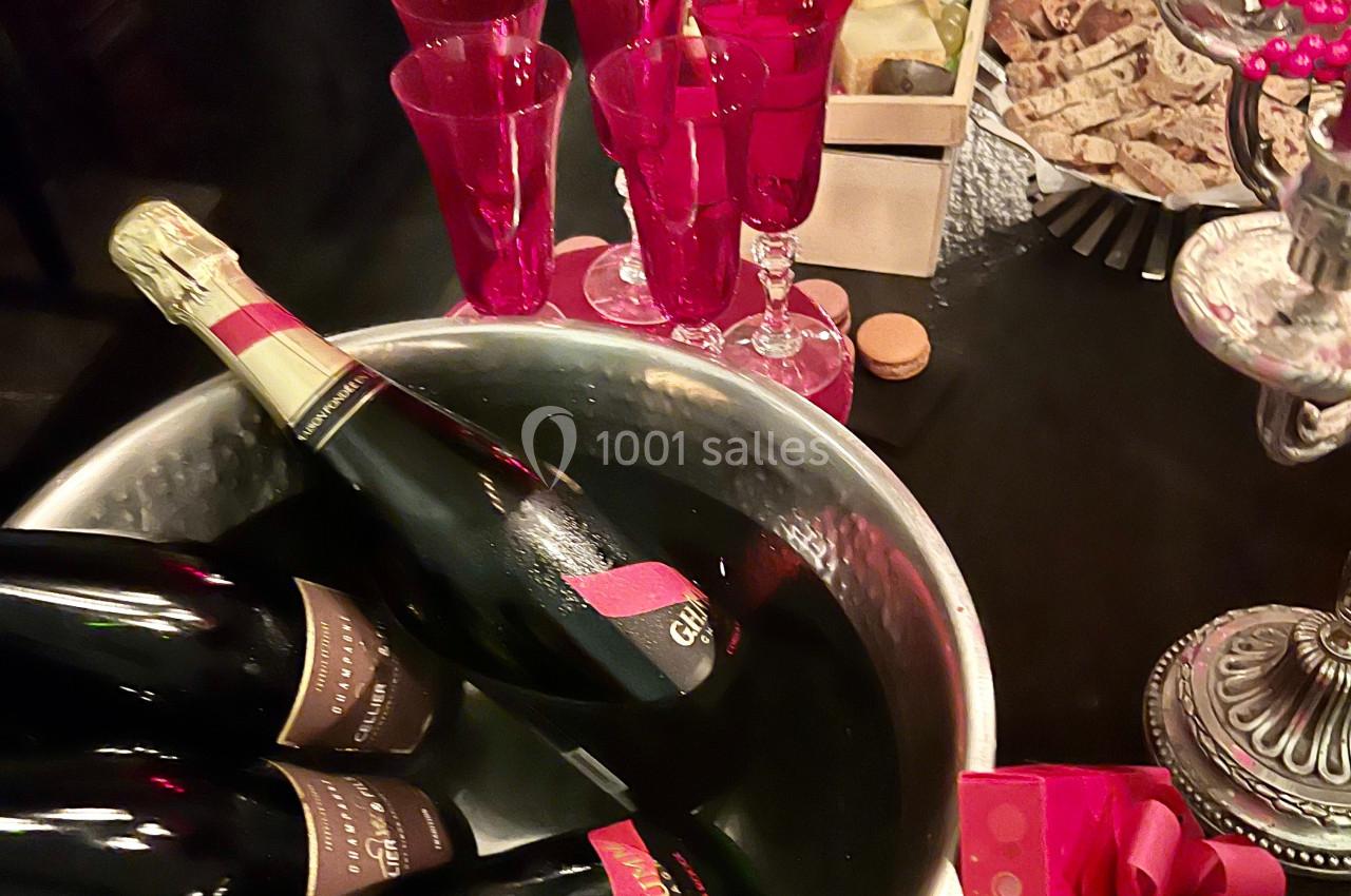 Seau à champagne avec bouteilles, flûtes rouges, plateau de fromages et décorations festives sur une table.