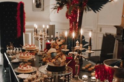 Salle à manger élégante avec table noire ornée, chandeliers, sculpture de panthère et tableau coloré au mur.