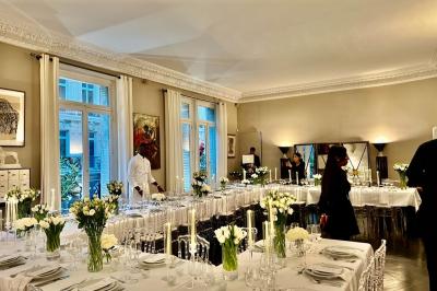Salle à manger élégante avec table noire ornée, chandeliers, sculpture de panthère et tableau coloré au mur.