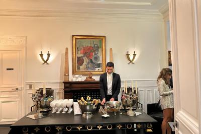 Salle à manger élégante avec table noire ornée, chandeliers, sculpture de panthère et tableau coloré au mur.