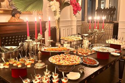 Salle à manger élégante avec table noire ornée, chandeliers, sculpture de panthère et tableau coloré au mur.