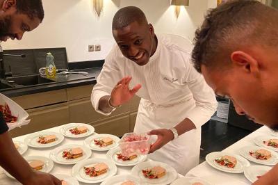 Salle à manger élégante avec table noire ornée, chandeliers, sculpture de panthère et tableau coloré au mur.