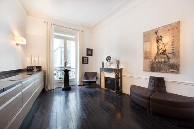 Salle à manger élégante avec table noire ornée, chandeliers, sculpture de panthère et tableau coloré au mur.