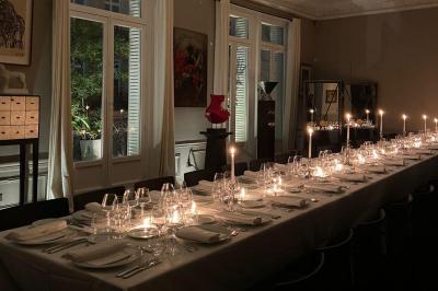 Salle à manger élégante avec table noire ornée, chandeliers, sculpture de panthère et tableau coloré au mur.