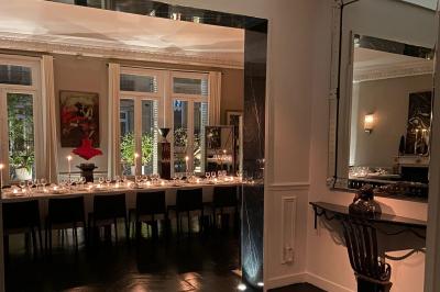 Salle à manger élégante avec table noire ornée, chandeliers, sculpture de panthère et tableau coloré au mur.