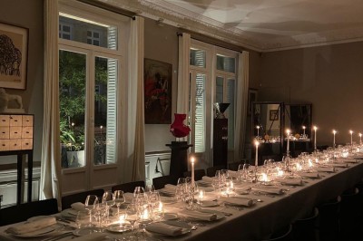 Salle à manger élégante avec table noire ornée, chandeliers, sculpture de panthère et tableau coloré au mur.