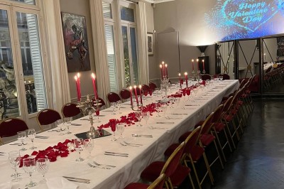 Salle à manger élégante avec table noire ornée, chandeliers, sculpture de panthère et tableau coloré au mur.