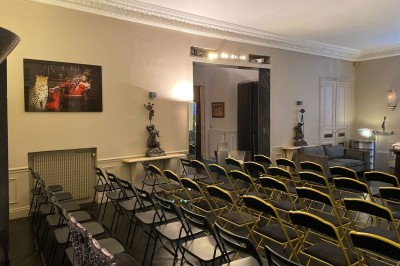 Salle à manger élégante avec table noire ornée, chandeliers, sculpture de panthère et tableau coloré au mur.