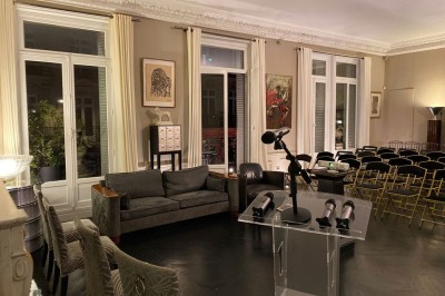 Salle à manger élégante avec table noire ornée, chandeliers, sculpture de panthère et tableau coloré au mur.