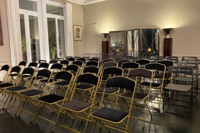 Salle à manger élégante avec table noire ornée, chandeliers, sculpture de panthère et tableau coloré au mur.