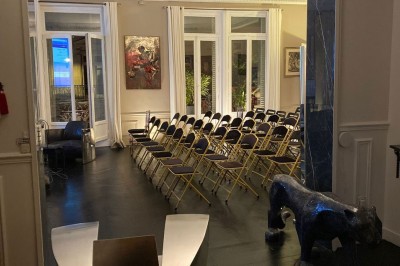 Salle à manger élégante avec table noire ornée, chandeliers, sculpture de panthère et tableau coloré au mur.