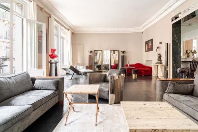 Salle à manger élégante avec table noire ornée, chandeliers, sculpture de panthère et tableau coloré au mur.