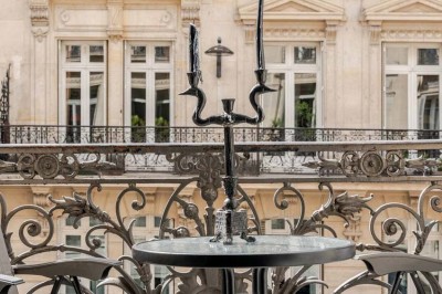 Salle à manger élégante avec table noire ornée, chandeliers, sculpture de panthère et tableau coloré au mur.