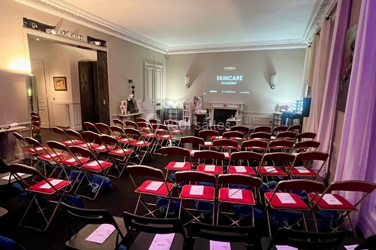 Salle de conférence avec des rangées de chaises pliantes, écran de projection et matériel de présentation.