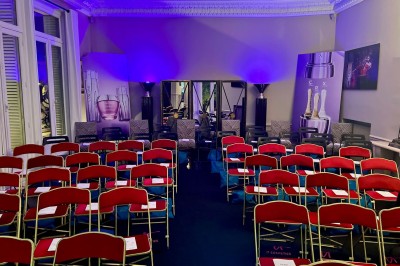 Salle à manger élégante avec table noire ornée, chandeliers, sculpture de panthère et tableau coloré au mur.