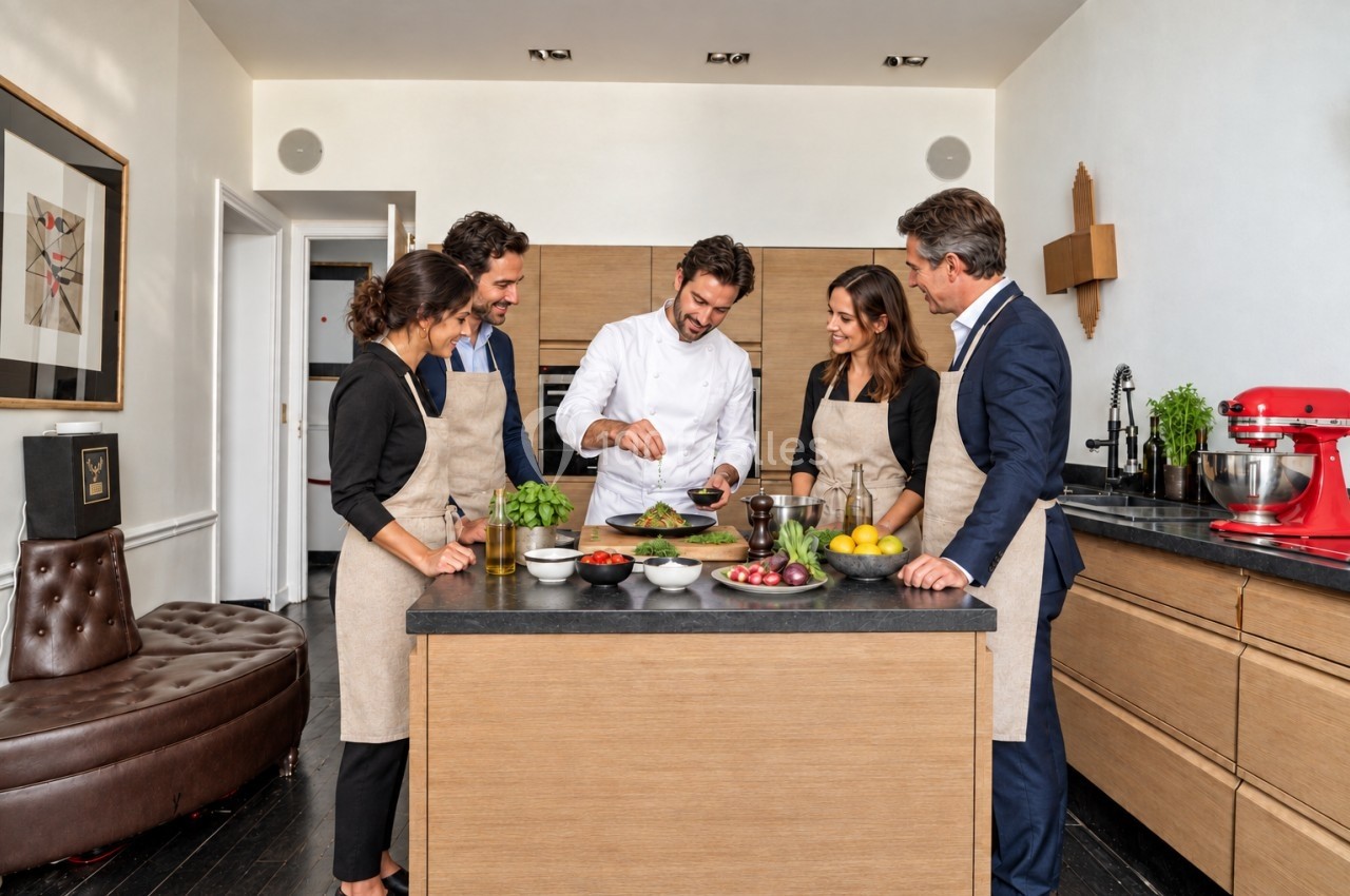 Un chef montre une préparation culinaire à quatre personnes portant des tabliers dans une cuisine moderne.