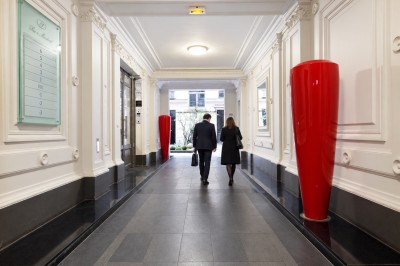 Miniature Location salle Paris 8 (Paris) - Le Loft Triangle d'Or Champs-Élysées #48 Un homme et une femme marchent dans un couloir élégant avec des colonnes blanches et de grands vases rouges.