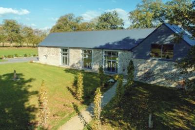 Vue aérienne d'une campagne avec des champs, des arbres, des maisons et des routes annotées pour indiquer des directions.