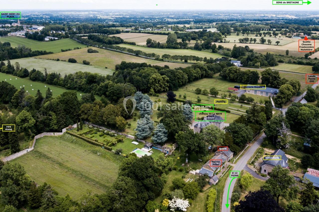 Vue aérienne d'une campagne avec des champs, des arbres, des maisons et des routes annotées pour indiquer des directions.