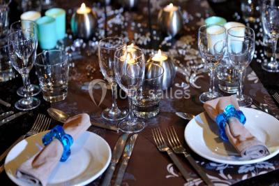 Table de réception élégamment dressée avec menu, verres, et centre de table floral composé de roses rouges et blanches.