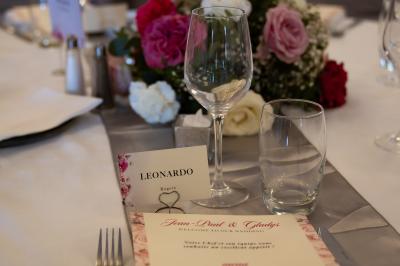 Table de réception élégamment dressée avec menu, verres, et centre de table floral composé de roses rouges et blanches.